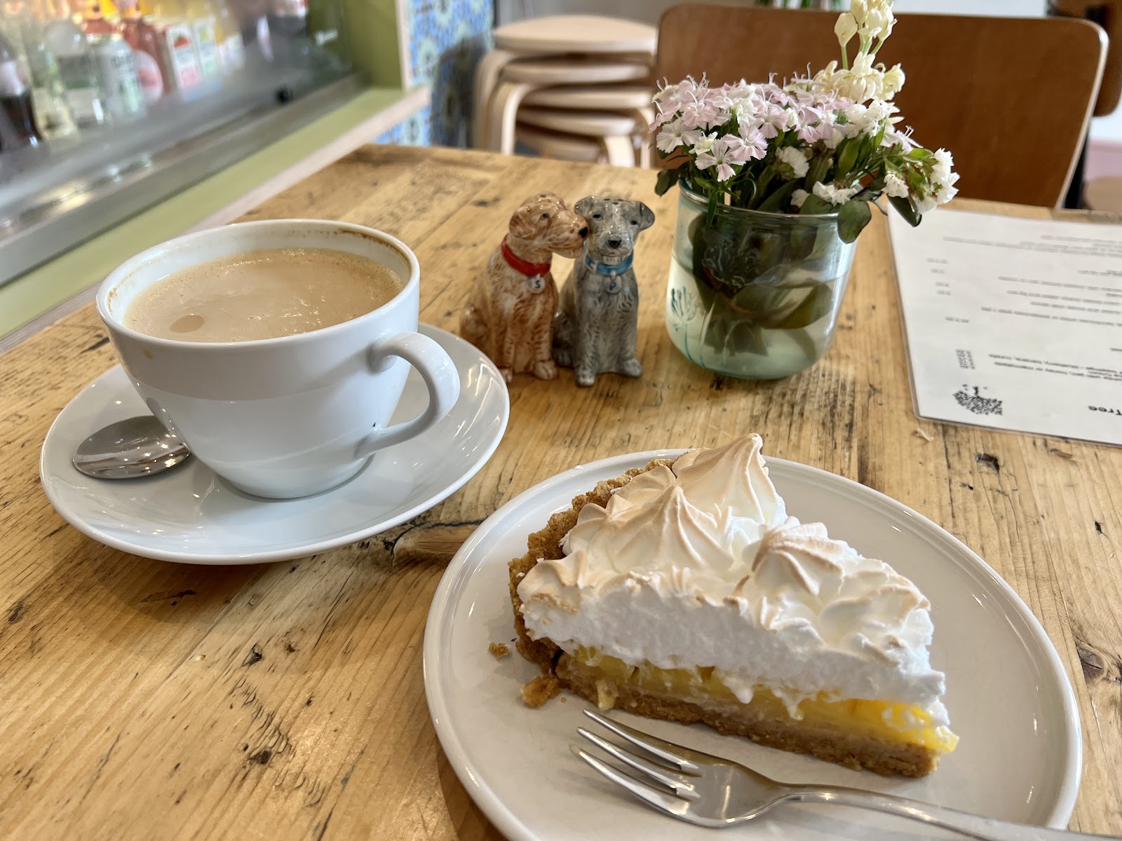 Lemon meringue tart and a white coffee on a wooden café table