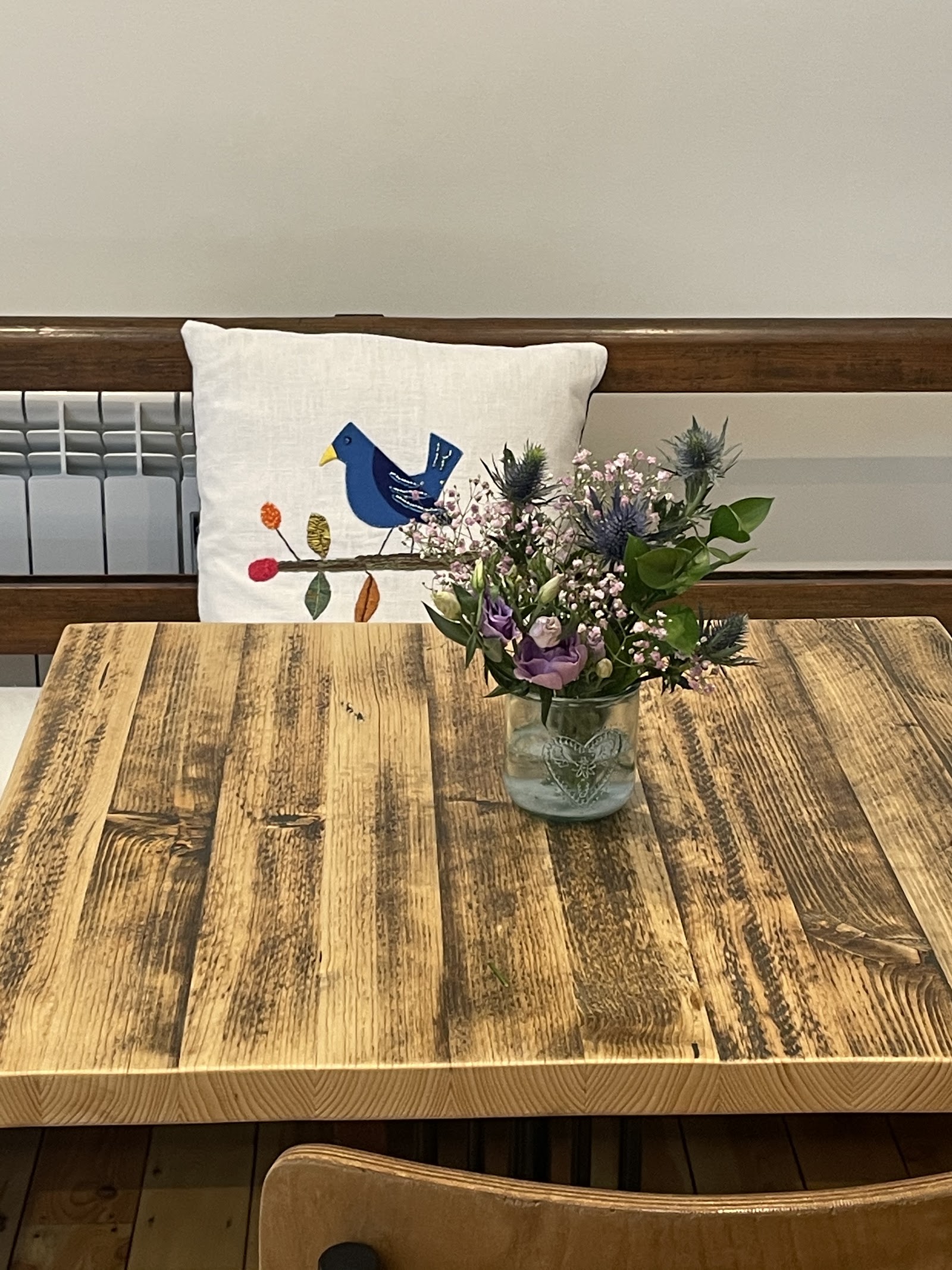 A rustic wooden table with a small wildflower jar at The Coffee Tree